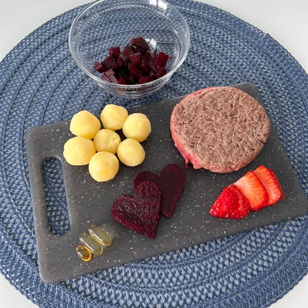 Gli ingredienti di una dieta casalinga: carne, patate, barbabietola, fragole e capsule di integratore